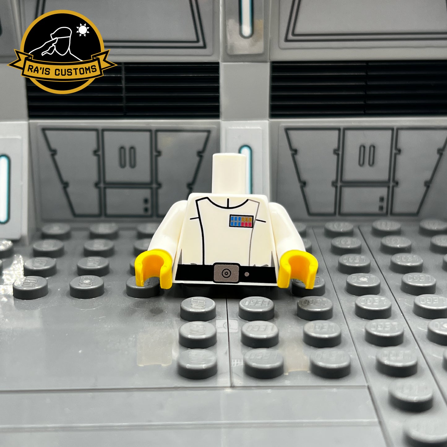 Pad-printed custom LEGO torso of a Grand Admiral from Star Wars, created by Ra'is Customs. This design is inspired by the Star Wars Expanded Universe and Star Wars Legends, including characters like Grand Admiral Thrawn from Legends. Features the iconic white Imperial uniform with accurate rank insignia and black belt detailing. Displayed in a Star Wars-themed diorama with a futuristic gray backdrop, this piece is perfect for collectors and fans of custom LEGO minifigures representing iconic figures.