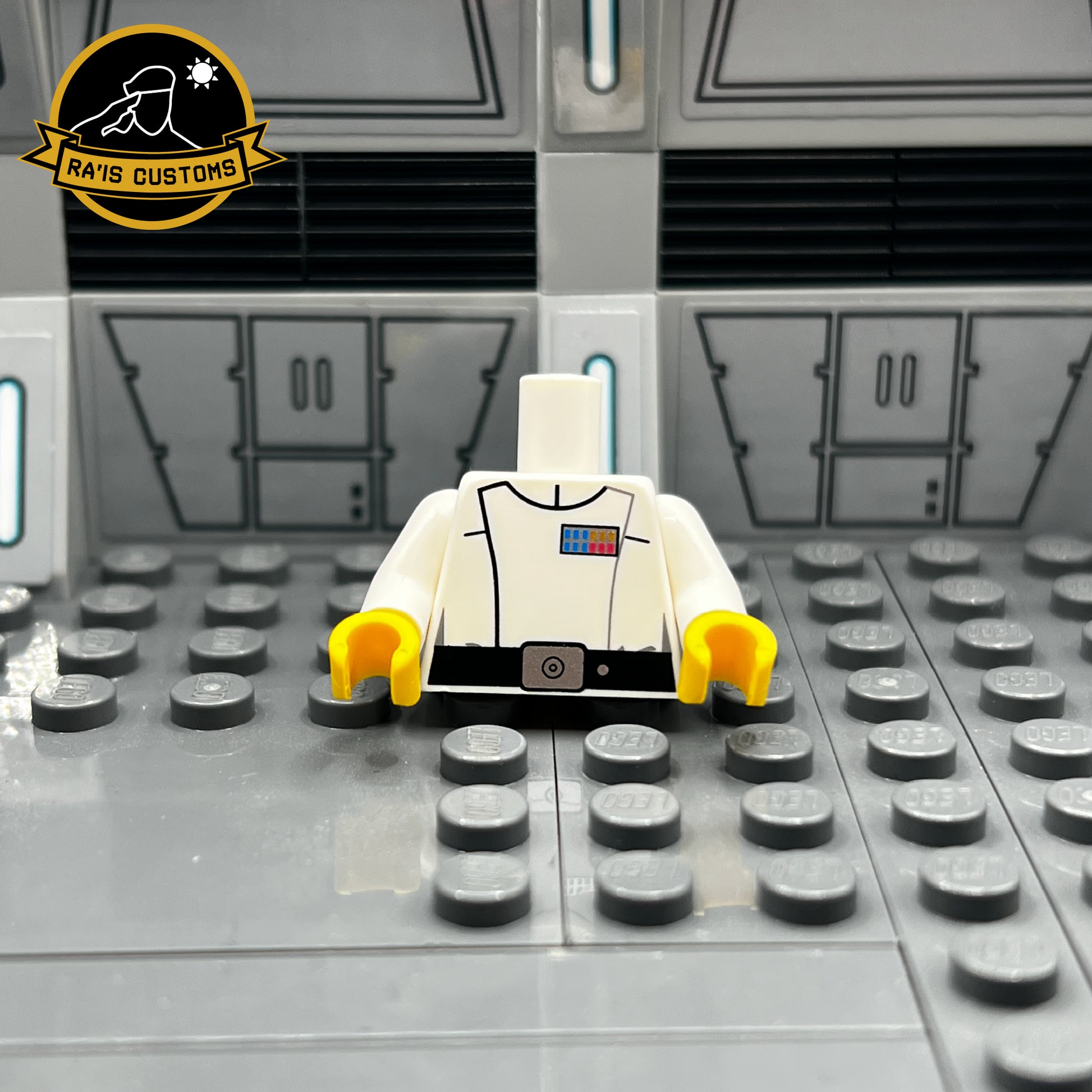 Pad-printed custom LEGO torso of a Grand Admiral from Star Wars, created by Ra'is Customs. This design is inspired by the Star Wars Expanded Universe and Star Wars Legends, including characters like Grand Admiral Thrawn from Legends. Features the iconic white Imperial uniform with accurate rank insignia and black belt detailing. Displayed in a Star Wars-themed diorama with a futuristic gray backdrop, this piece is perfect for collectors and fans of custom LEGO minifigures representing iconic figures.