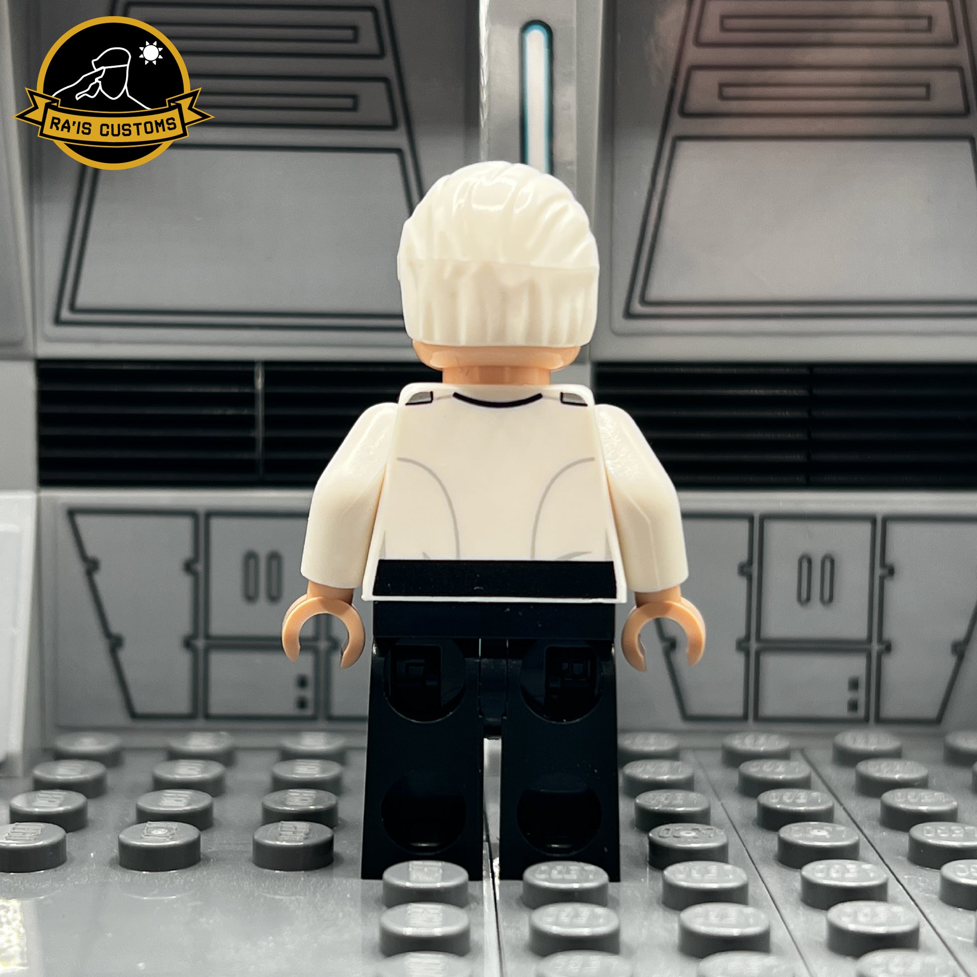 Rear view of a pad-printed custom LEGO minifigure of Colonel Yularen from Star Wars, created by Ra'is Customs. Displays the back of the Imperial uniform with fine detailing and clean craftsmanship, showcasing the accuracy of Galactic Empire officer designs. Set in a Star Wars-themed diorama with a futuristic gray backdrop, this figure highlights the premium quality of custom-made LEGO Imperial minifigures.